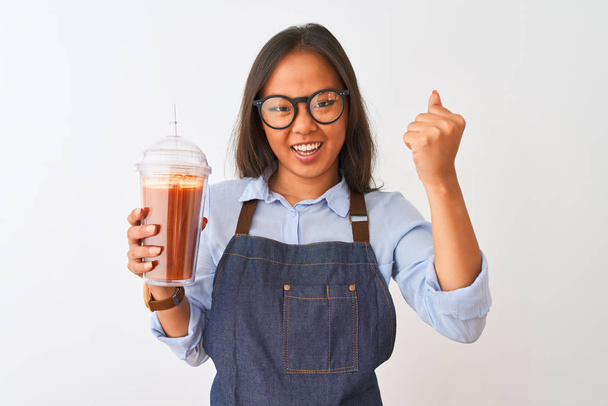 Chinese woman wearing glasses apron drinking smoothie over isolated white background annoyed and frustrated shouting with anger, crazy and yelling with raised hand, anger concept - Photo, Image