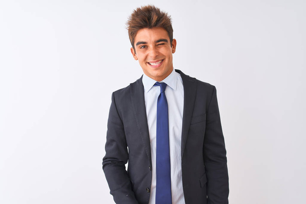 Jonge knappe zakenman draagt pak staan over geïsoleerde witte achtergrond knipogen naar de camera met sexy uitdrukking, vrolijk en gelukkig gezicht. - Foto, afbeelding