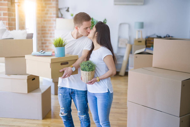 Young beautiful couple sitting on the floor at new home around cardboard boxes skeptic and nervous, disapproving expression on face with crossed arms. Negative person. - Photo, Image