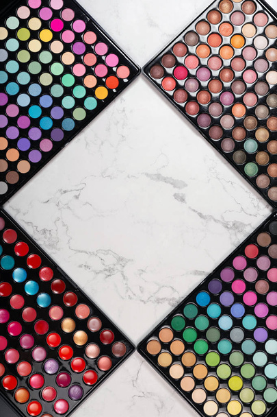 Flat lay of cosmetic eyeshadow palettes on white marble background - Фото, зображення