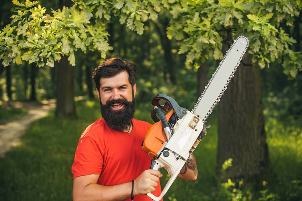 Handsome young man with axe near forest. The Lumberjack working in a forest. Logging. - Фото, изображение