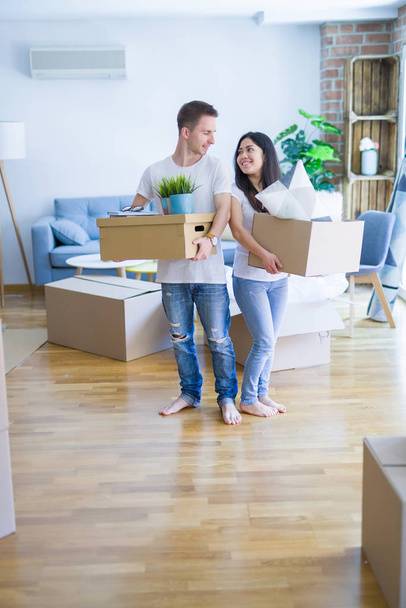 Young beautiful couple sitting on the floor at new home around cardboard boxes skeptic and nervous, disapproving expression on face with crossed arms. Negative person. - Foto, afbeelding