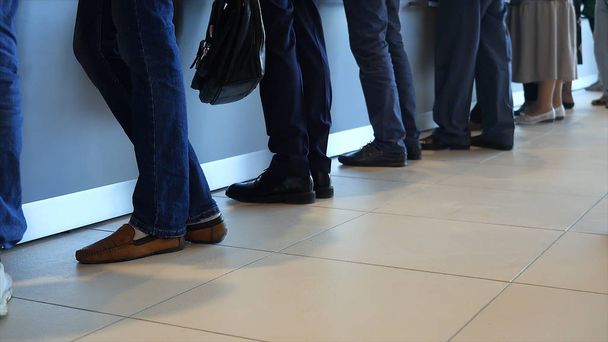 Вид на ноги клієнтів, що стоять в сучасному офісі, який обслуговується в банку. Медіа. Люди в черзі на службу в відділенні банку
. - Фото, зображення