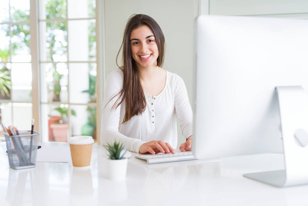 Gyönyörű fiatal üzleti nő dolgozik számítógéppel, mosolyogva - Fotó, kép