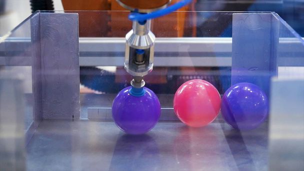 Primer plano para un robot recogiendo bolas de plástico de la caja de vidrio, Expo - exposición internacional. Medios. Antecedentes futuristas y científicos de una máquina que toma pequeñas bolas
. - Foto, Imagen