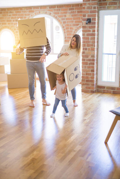 Belle famille avec enfant jouant avec des boîtes de fanny en carton à la nouvelle maison
 - Photo, image