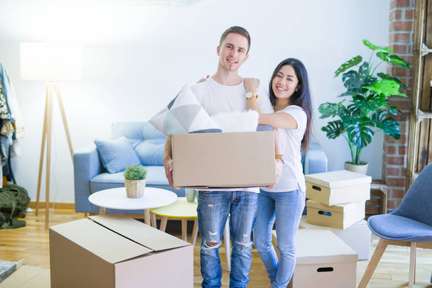 Young beautiful couple sitting on the floor at new home around cardboard boxes skeptic and nervous, disapproving expression on face with crossed arms. Negative person. - Photo, Image