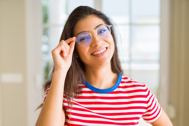 Νεαρή όμορφη γυναίκα χαμογελά χαρούμενο φορώντας γυαλιά που αναζητούν ευχαριστημένοι με ένα μεγάλο χαμόγελο - Φωτογραφία, εικόνα