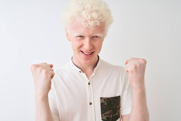 Young albino blond man wearing casual shirt standing over isolated white background screaming proud and celebrating victory and success very excited, cheering emotion - Foto, imagen