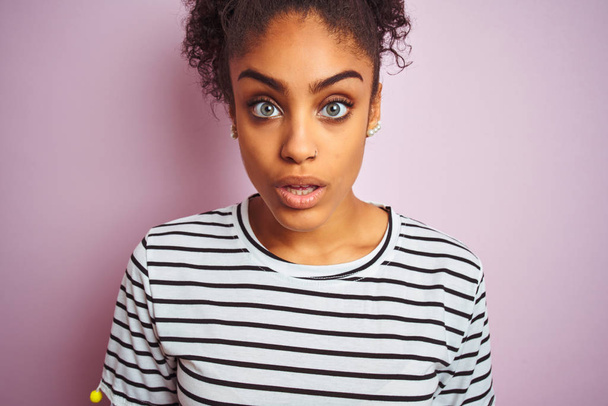 African american woman wearing navy striped t-shirt standing over isolated pink background scared in shock with a surprise face, afraid and excited with fear expression - Foto, Imagen