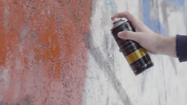 Mano sosteniendo una lata de pintura en aerosol y dibujando graffiti colorido en la pared, concepto de arte urbano. Acción. Vista lateral de una pintura de artista con aerosol en la pared, trabajos de pintura de hormigón
. - Foto, Imagen