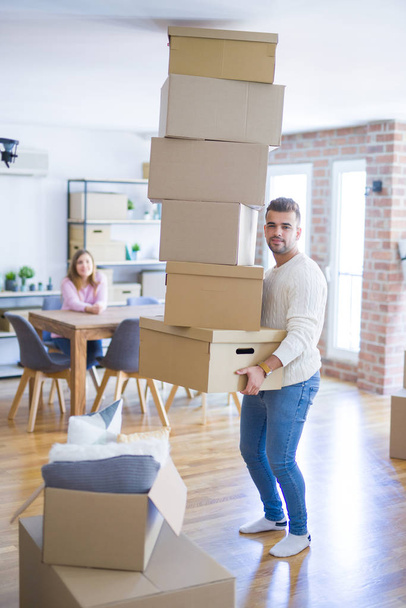 Young couple moving to a new house, man holding cardboard boxes  - Photo, Image