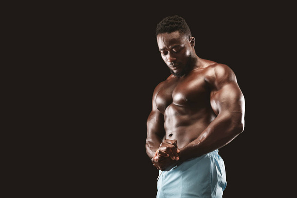 黒いスタジオで筋肉の胸を示すアフリカのボディービルダー - 写真・画像