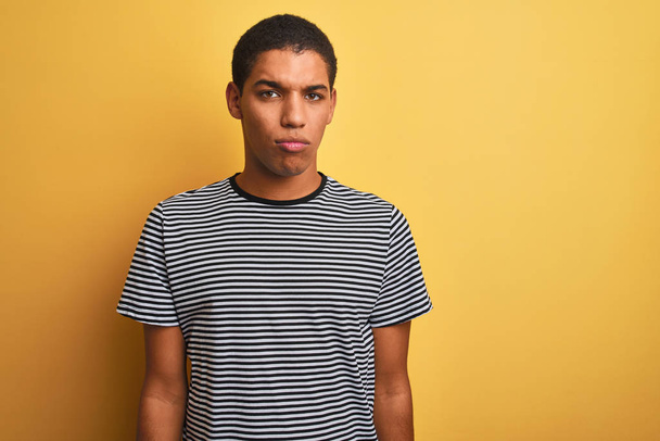 Young handsome arab man wearing navy striped t-shirt over isolated yellow background depressed and worry for distress, crying angry and afraid. Sad expression. - Photo, image