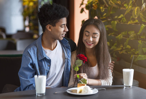Αφρικανική έφηβος τύπος εντυπωσιάζει την κοπέλα του με τριαντάφυλλο - Φωτογραφία, εικόνα