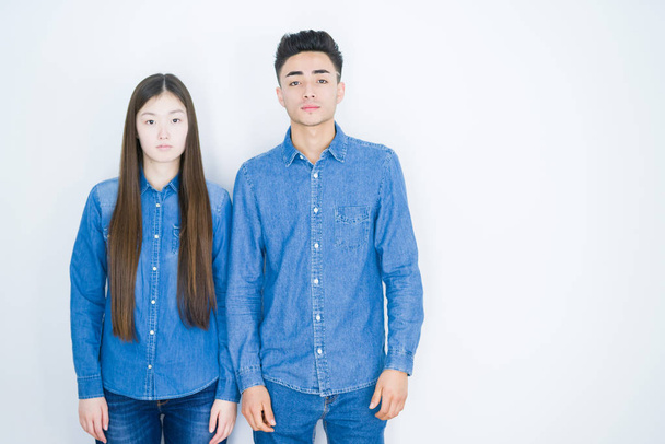 Bella giovane coppia asiatica su sfondo bianco isolato Rilassato con espressione seria sul viso. Semplice e naturale guardando la fotocamera
. - Foto, immagini