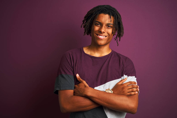 Afro man with dreadlocks wearing casual t-shirt standing over isolated purple background happy face smiling with crossed arms looking at the camera. Positive person. - Fotografie, Obrázek