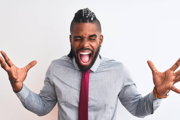 Homme d'affaires afro-américain avec des tresses portant cravate debout sur fond blanc isolé célébrant fou et fou de succès avec les bras levés et les yeux fermés hurlant excité. Concept gagnant
 - Photo, image