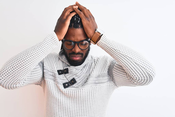 Uomo afroamericano indossa maglione grigio e occhiali su sfondo bianco isolato che soffre di mal di testa disperato e stressato perché il dolore e l'emicrania. Mani sopra la testa
. - Foto, immagini