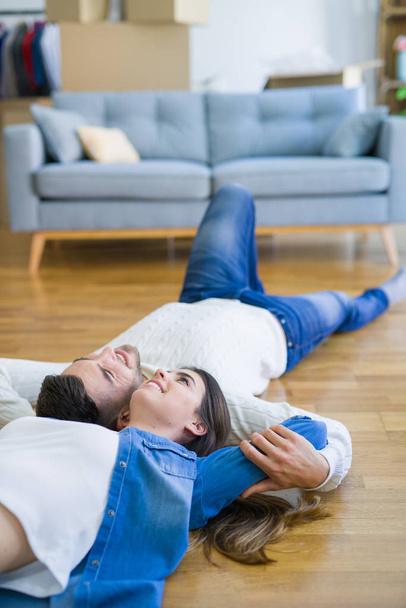 Young beautiful couple lying on the floor of new house, smiling  - Foto, Imagem