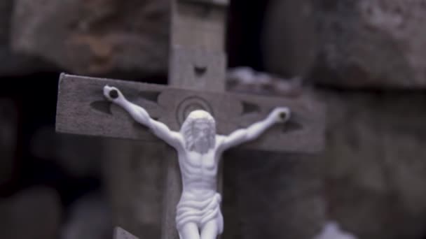 Feche-se para a cruz de madeira com Jesus crucificado em tijolos de pedra fundo, Bíblia e conceito de religião. Filmagem. Atributo religioso da igreja, simbolismo cristão
. - Filmagem, Vídeo
