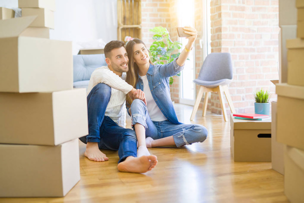 Young couple sitting on the floor of new house taking a selfie p - Photo, Image