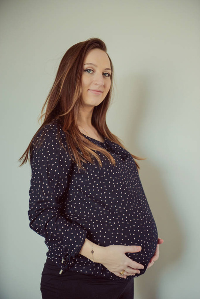 Mulher grávida fica atrás da barriga
 - Foto, Imagem
