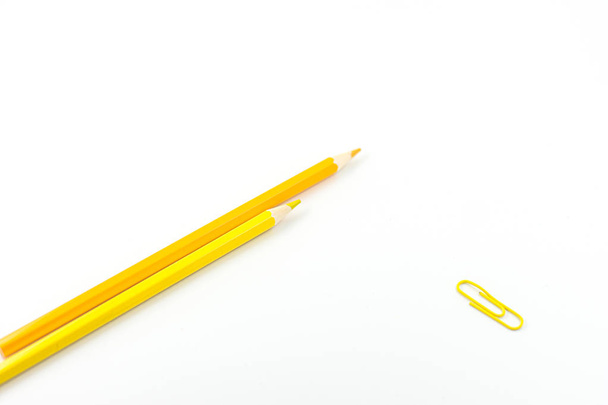 Deux crayons jaunes et trombone jaune sur fond blanc. Concentration sélective
 - Photo, image