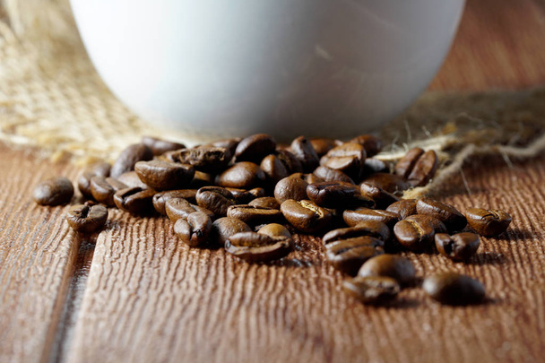 coffee beans on table and partial view of cup  - Foto, immagini