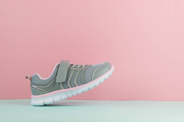 Walking Grey sneaker met rechter voet op roze en blauwe achtergrond. - Foto, afbeelding