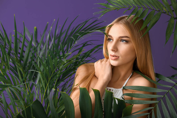 Retrato de mujer hermosa con hojas tropicales sobre fondo ultravioleta
 - Foto, Imagen