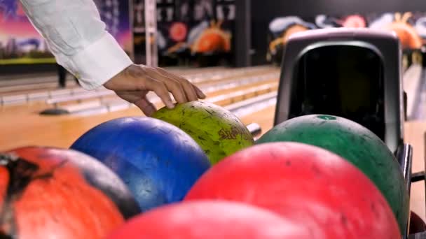 Közel ahhoz, hogy férfi kéz vesz egy labdát dobás előtt bowling közben egy bowling klubban. A média. Sport és szórakozás koncepció, férfi vesz egy labdát az állványról. - Felvétel, videó