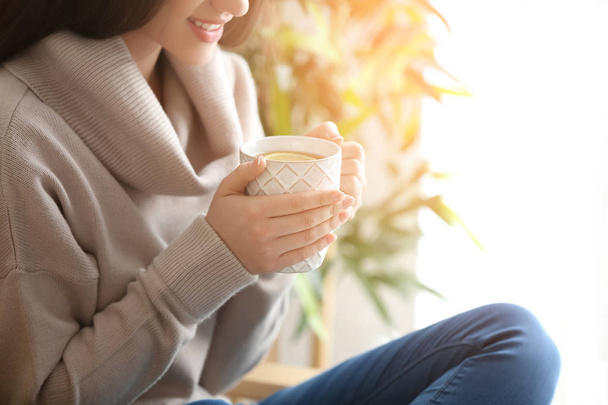 Beautiful young woman with cup of hot tea at home - Fotografie, Obrázek