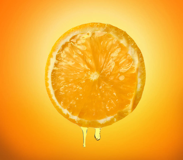 Aceite esencial que gotea de la rebanada de naranja en el fondo del color
 - Foto, imagen