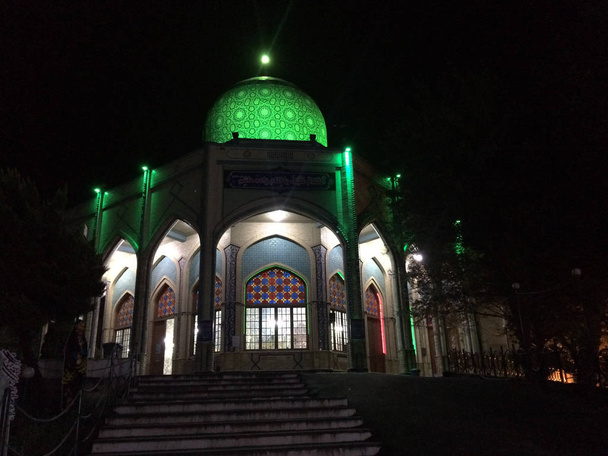 Gilan, Iran - summer, 2018: The shrine of Imam Zadeh Hashem outside the city of Gilan, green light dome in the dark of the night - Photo, Image