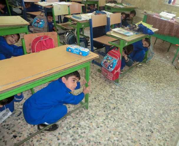 地震操縦小学生の男の子。小学生の男の子の地震操縦。イランの学校で地震被害を減らすための生徒の指導 - 写真・画像