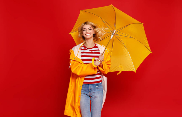 junges fröhliches emotionales fröhliches Mädchen lacht mit gelbem Regenschirm - Foto, Bild