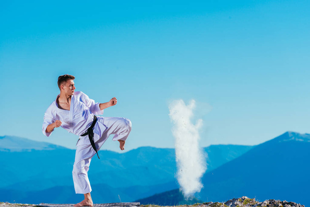 Fit karate athlete kicking a cup filled whit fluor causing a big - Photo, Image