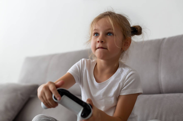Competitive girl playing with gamepad on couch - Valokuva, kuva