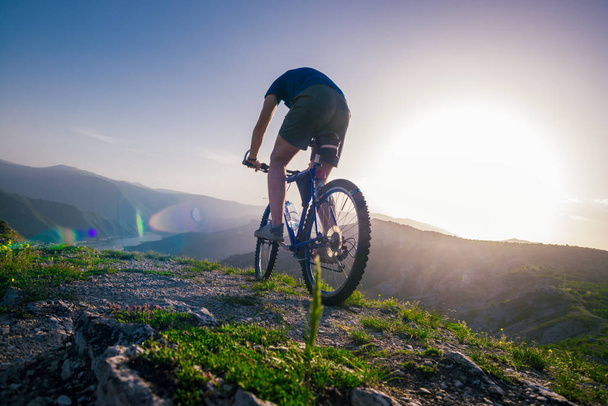 Περιπετειώδης ποδηλάτης ιππασία ποδήλατο βουνό του στην άκρη ενός cl - Φωτογραφία, εικόνα