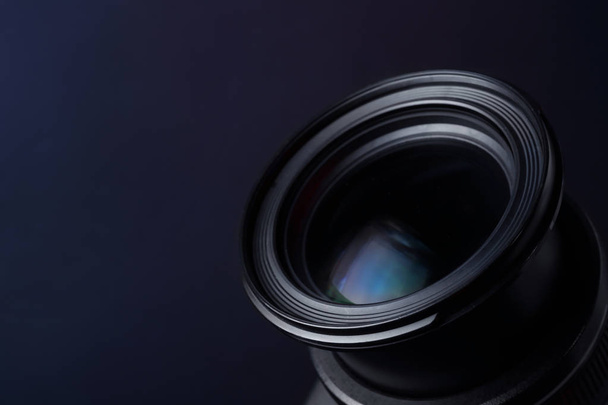 Lens of professional camera on dark blue background, closeup. Space for text - Fotó, kép