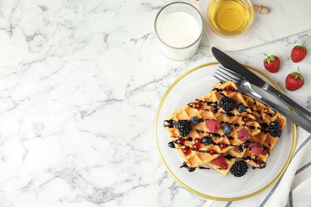 Delicious waffles with fresh berries served on white marble table, flat lay. Space for text - Foto, immagini