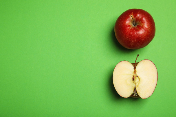 Flat lay composition with ripe juicy red apples on green background, space for text - 写真・画像