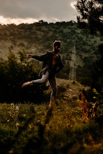 Позитивный веселый беззаботный беззаботный молодой человек во время танцев на горном холме
 - Фото, изображение