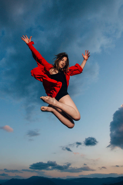 Uma mulher bailarina bailarina bailarina bailarina dançando em silhueta sobre céu nublado - Foto, Imagem