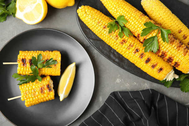 Flat lay composition of grilled corn cobs on grey table - Fotografie, Obrázek