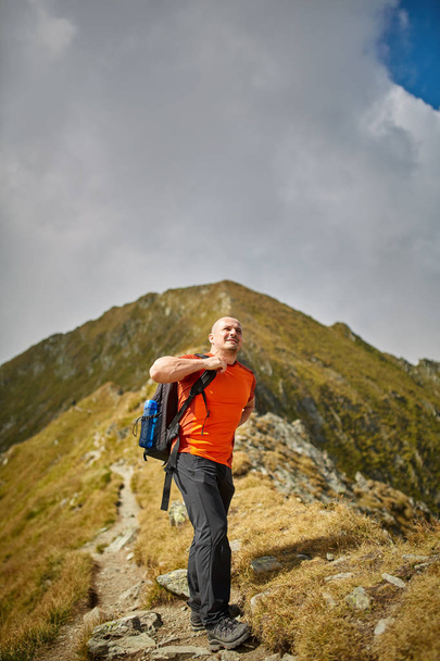 Man with camera and backpack hiking on a mountain trail - Foto, immagini