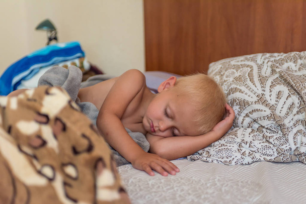 petit garçon blond dormant sur le lit
 - Photo, image