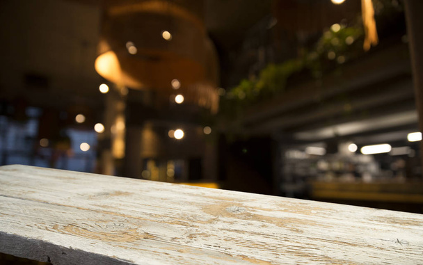 Пустая столешница из дерева на размытом светлом золотом боке кафе ресторана на тёмном фоне
 - Фото, изображение