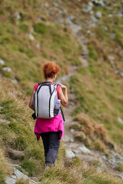Backpacker lady with camera hiking on a mountain trail - Photo, image